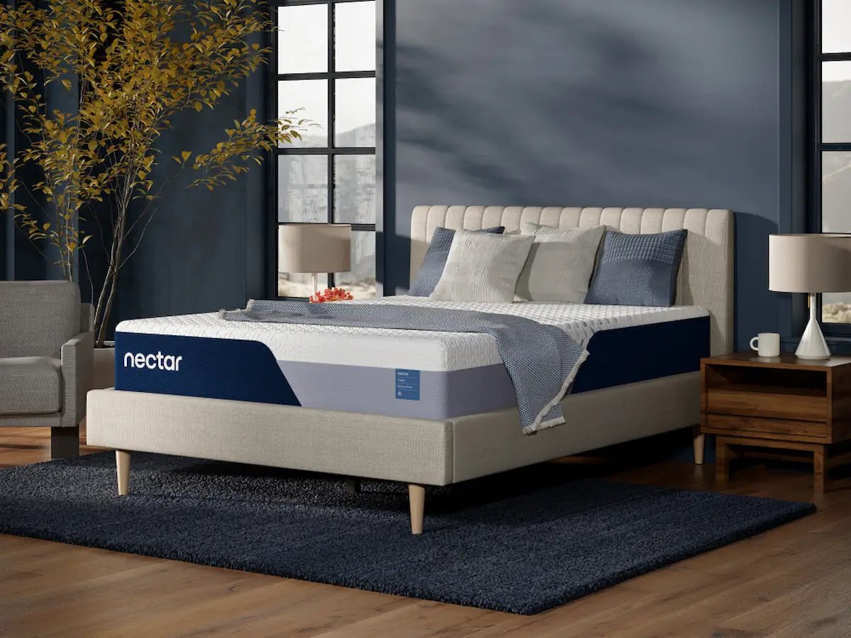 Nectar Classic Memory Foam mattress on a light upholstered bed in a navy bedroom, with a gray throw across its white top.