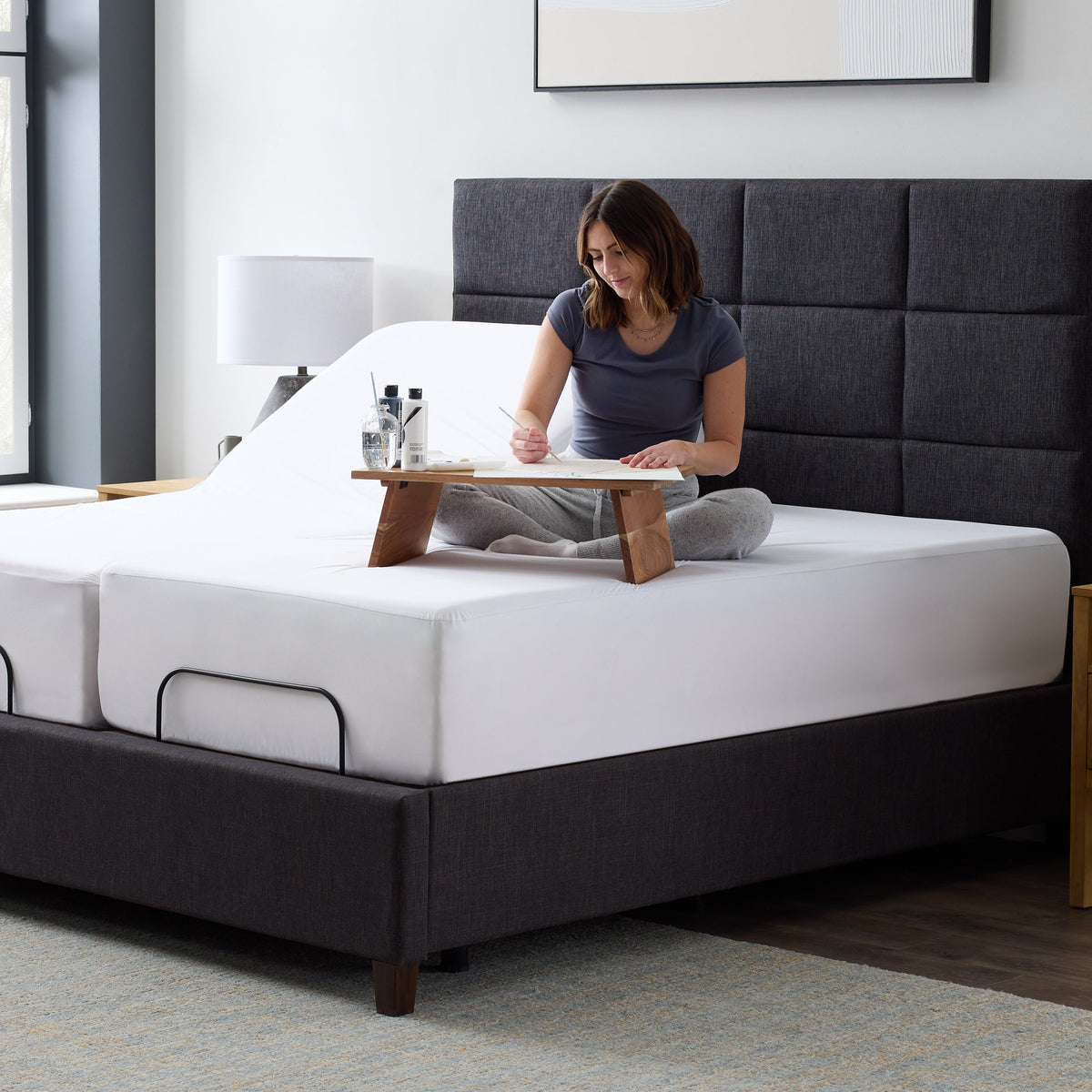 Malouf Five Sided Omniphase protector on a bed, three-quarter wide view