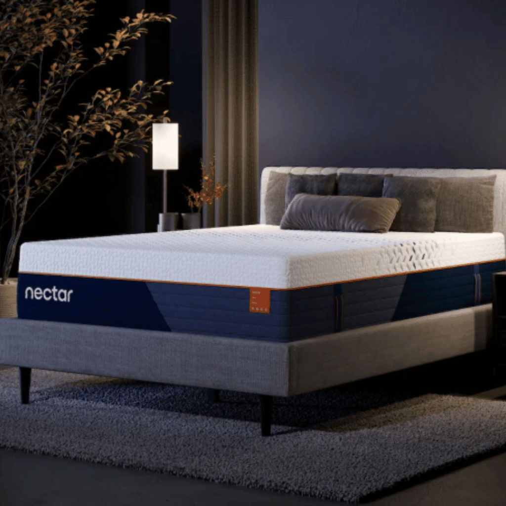 Nectar Ultra Hybrid mattress on a gray upholstered bed in a softly lit bedroom, with a white quilted top, navy side panels and orange trim.